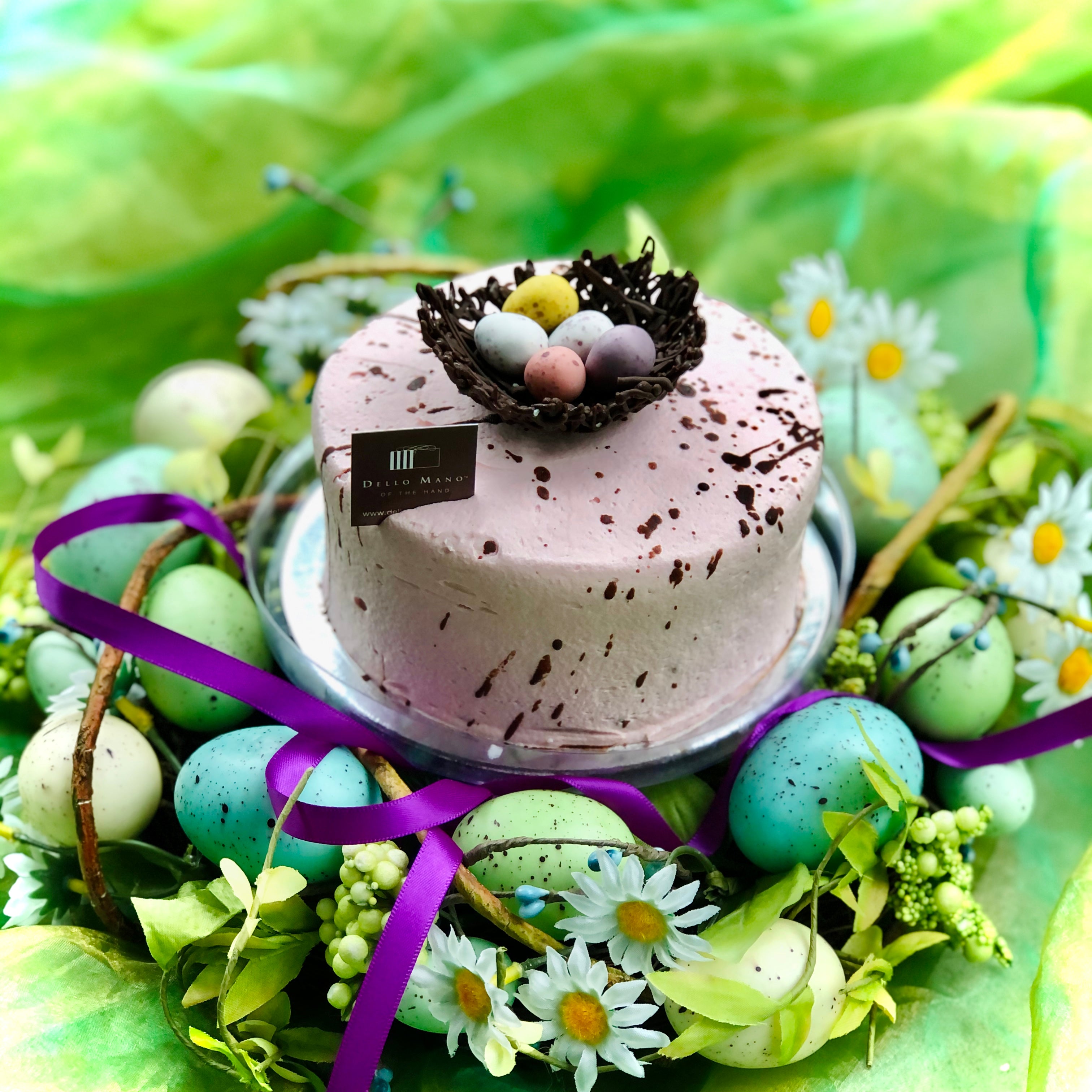 A dusty pink cake speckled with chocolate flecks and a chocolate nest with easter eggs on top.