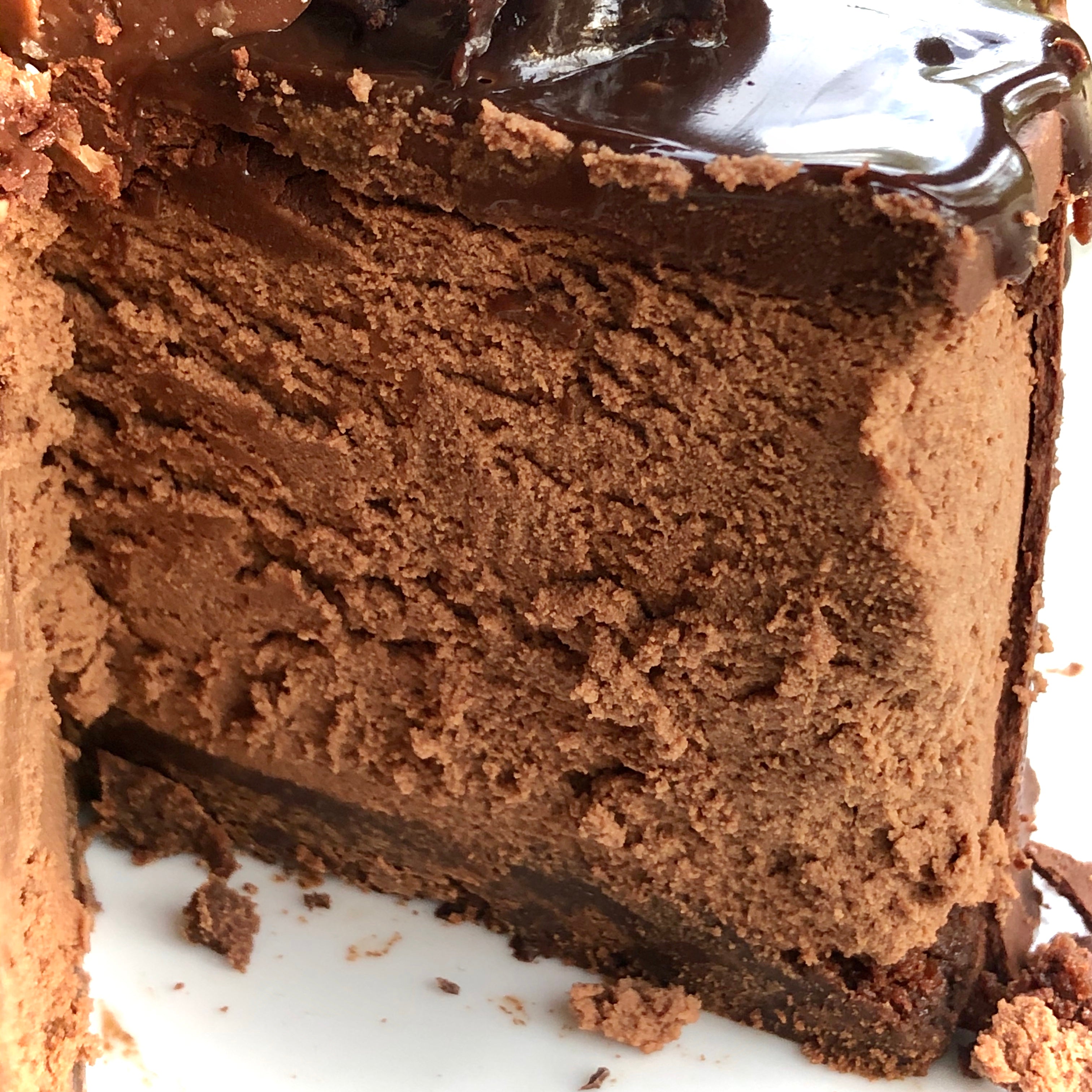 A cut slice of chocolate mousse cake with brownie base and fluffy velvet textured mousse.