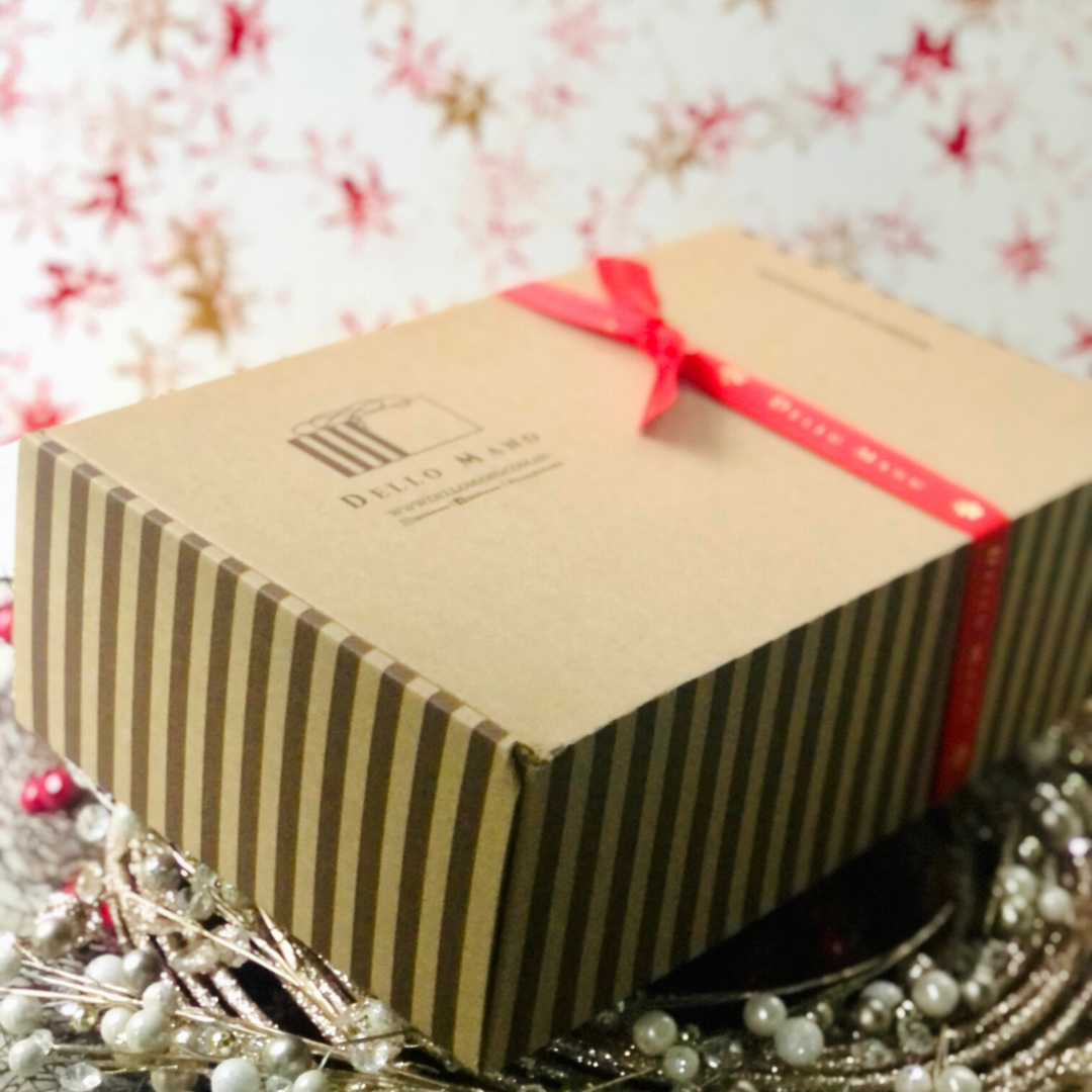 A hamper box with the words Dello Mano and a red ribbon that has a blurred Dello Mano printed on it.